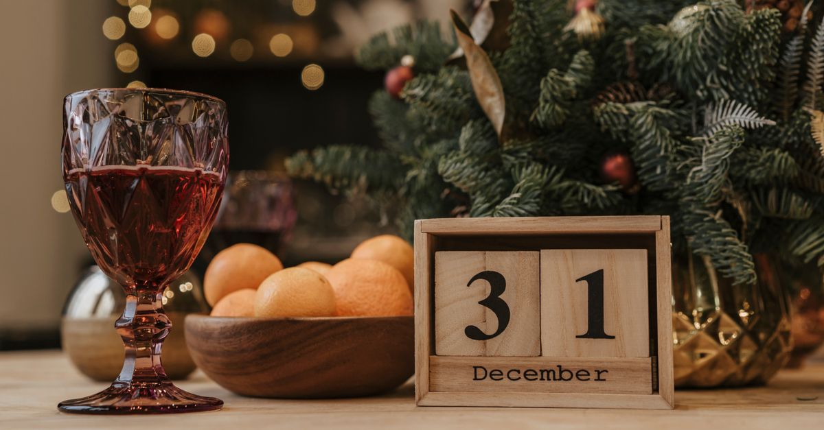 Festive New Year's Eve scene with a glass of red wine, December 31 calendar, and holiday decor.